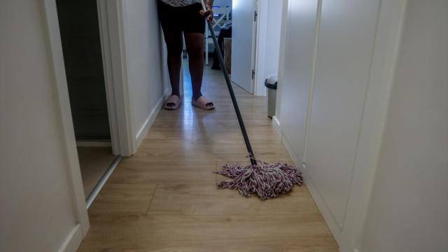 Una empleada de hogar limpia con una fregona.