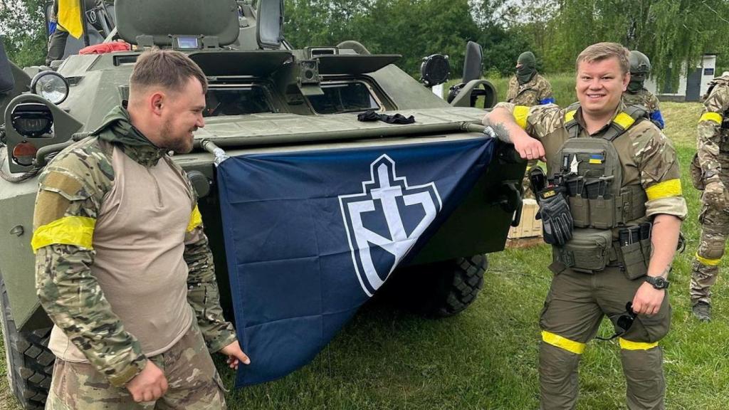 La imagen del folleto sin fecha muestra a miembros del Cuerpo de Voluntarios de Rusia junto a un vehículo blindado