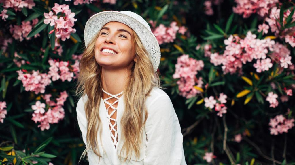 Mujer sonriendo con un fondo de flores. Foro: iStock.