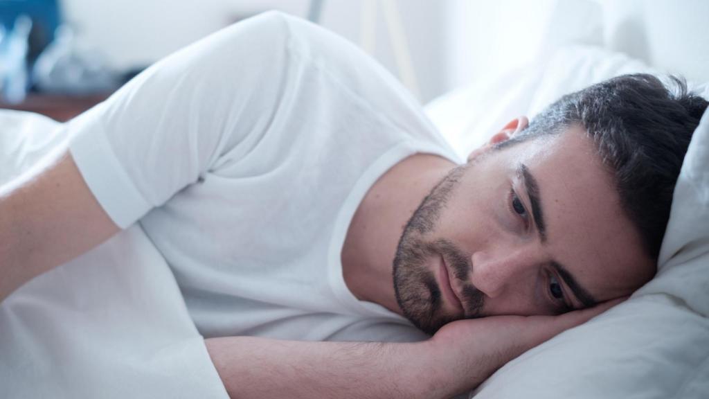 Un hombre preocupado en la cama.