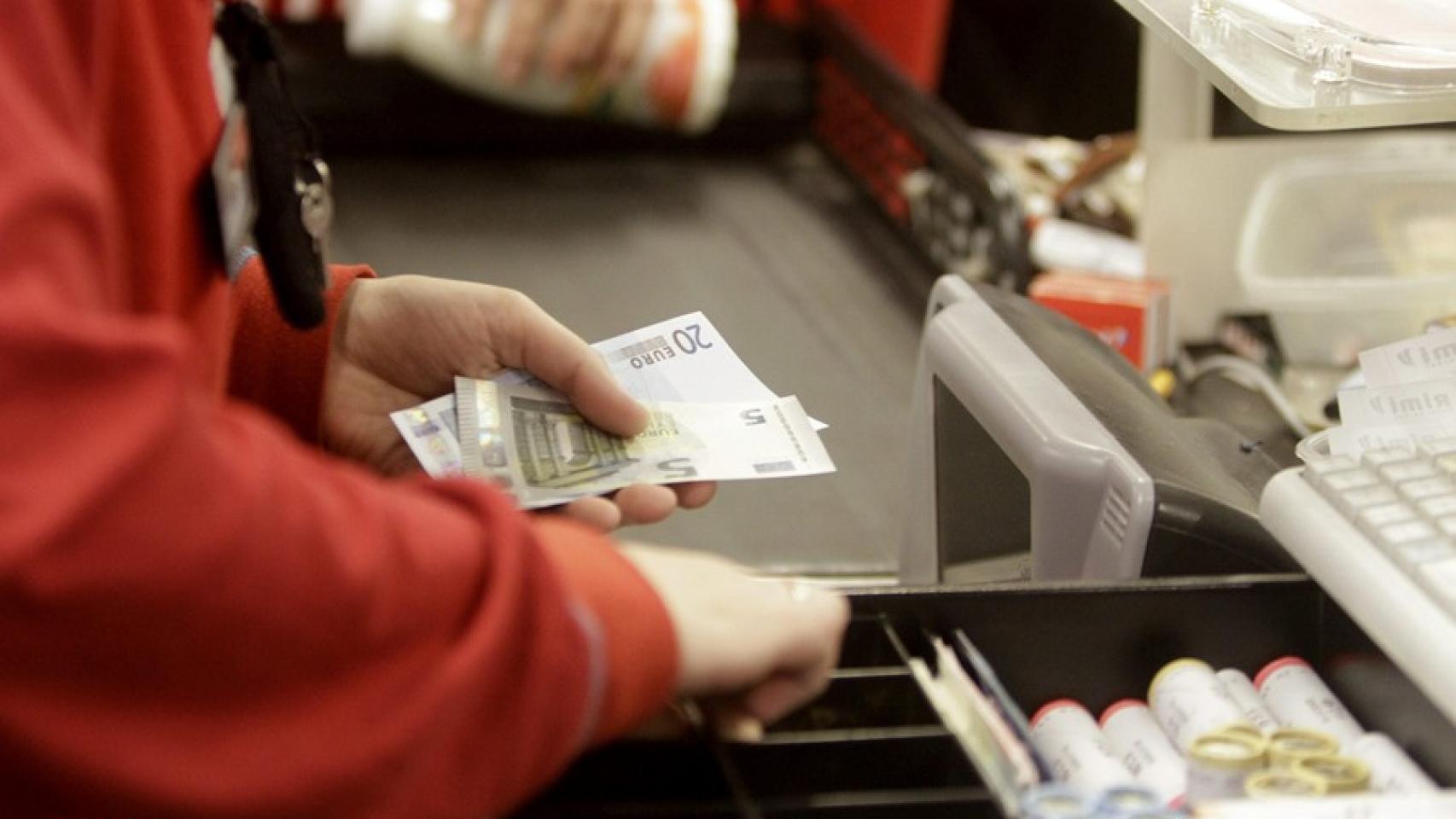 Una cajera de un supermercado devolviendo cambio a un cliente.