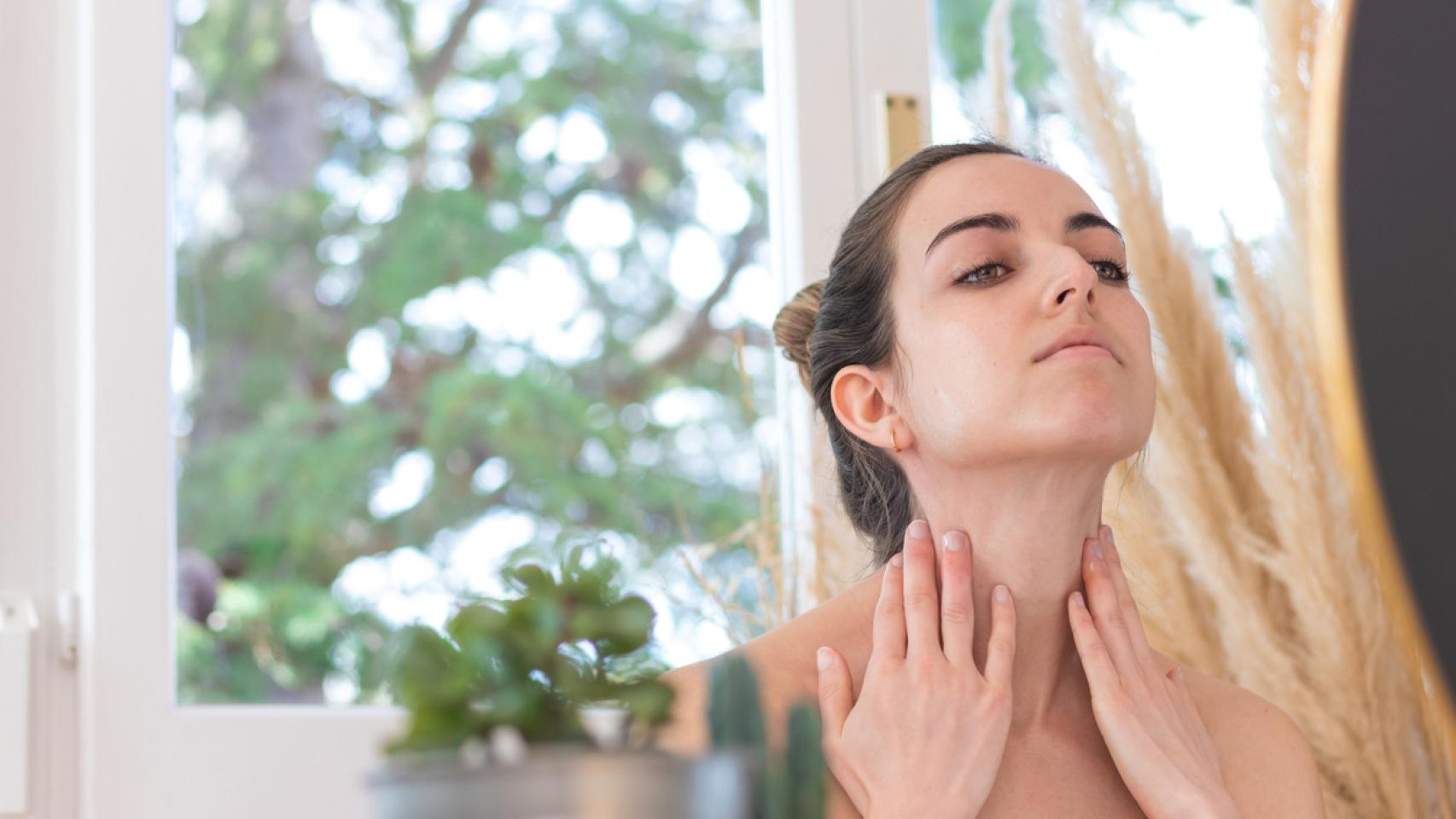 Mujer mirando su cuello ante el espejo.