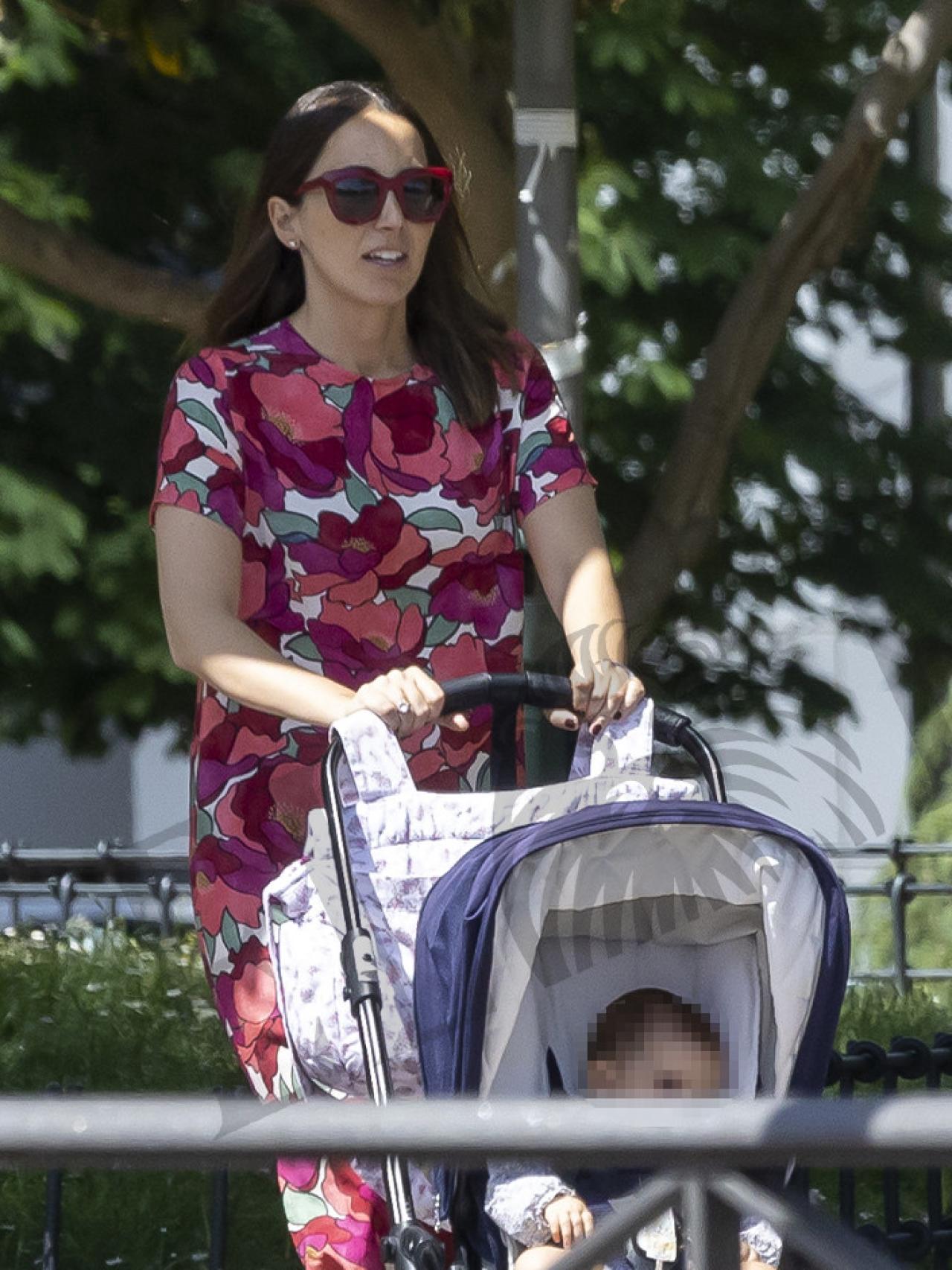 Alejandra Romero paseando a su hija menor, ataviada con un vestido floreado.