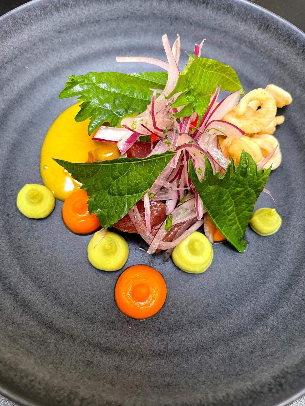 El ceviche de atún, leche tigre mango, aguacate, criolla, cremoso boniato, shisho, chicharrón  calamar.