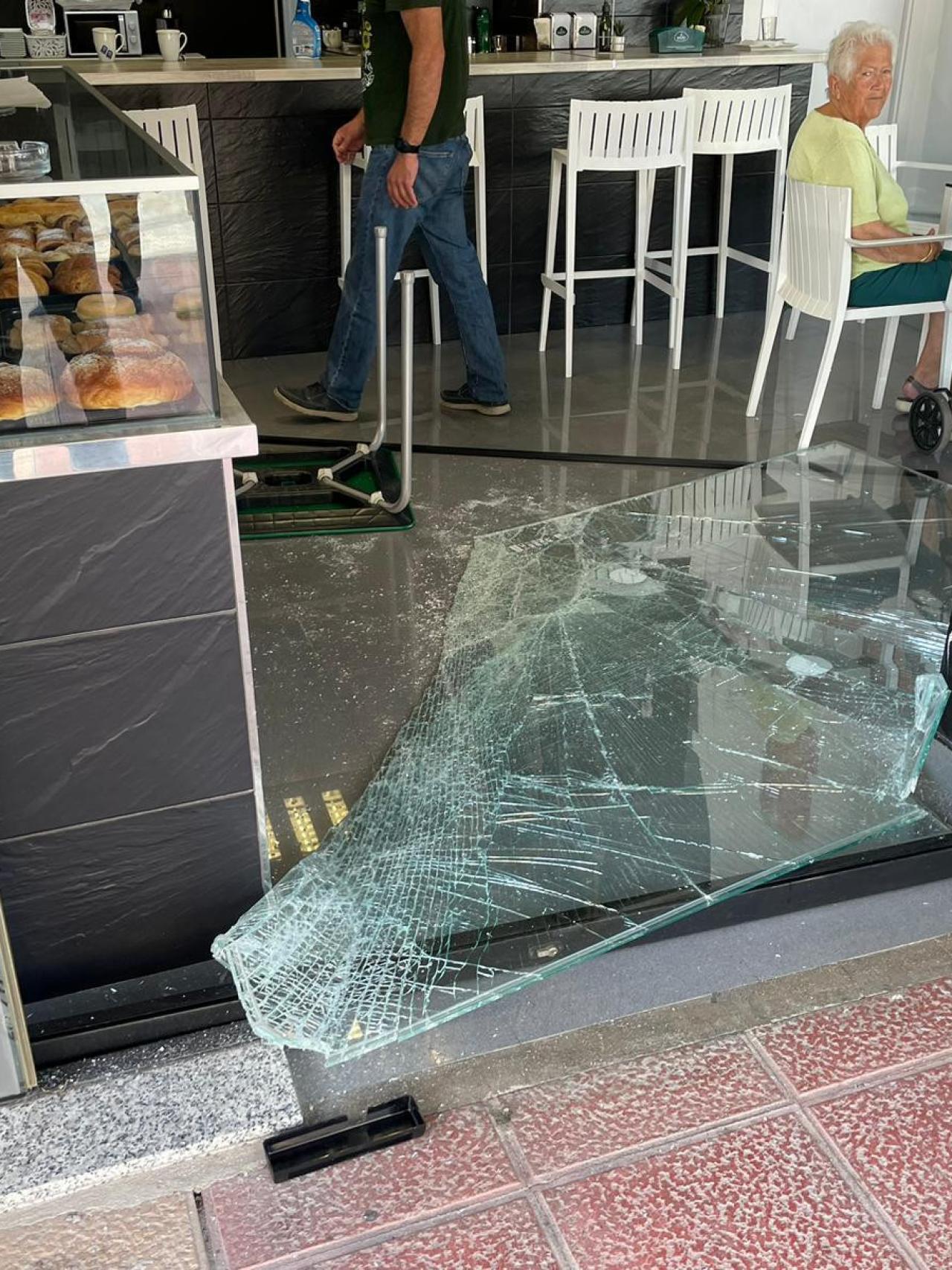 Una anciana, sentada en la Cafetería La Migaja, después de que un ciudadano marroquí se haya estampado contra la cristalera.