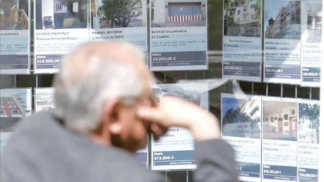 Una persona frente a una inmobiliaria, en imagen de archivo.