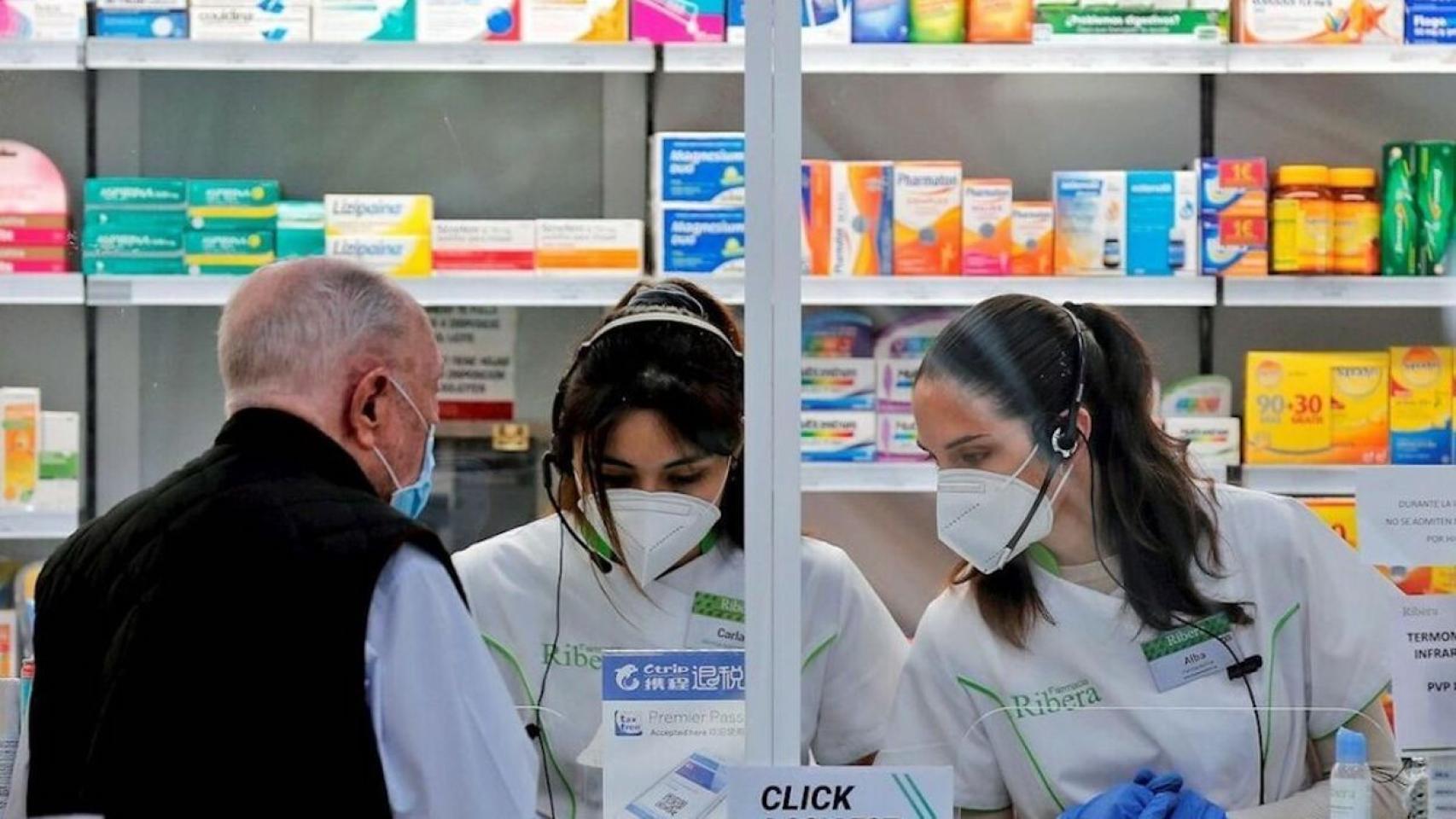 Empleadas de una farmacia atendiendo a un cliente, en imagen de archivo.