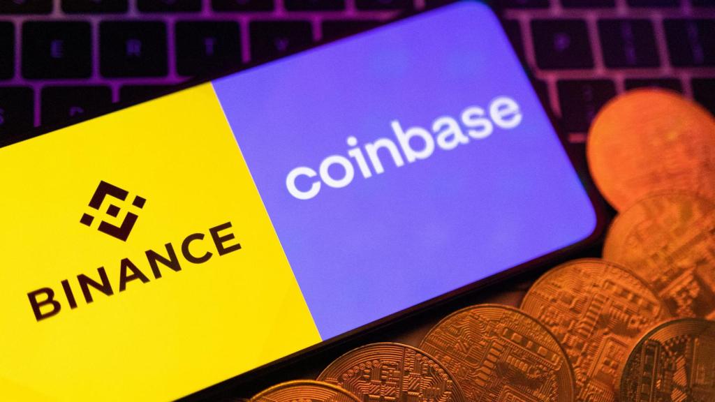 El logo de Coinbase y Binance en un teléfono sobre un teclado y varias criptodivisas.