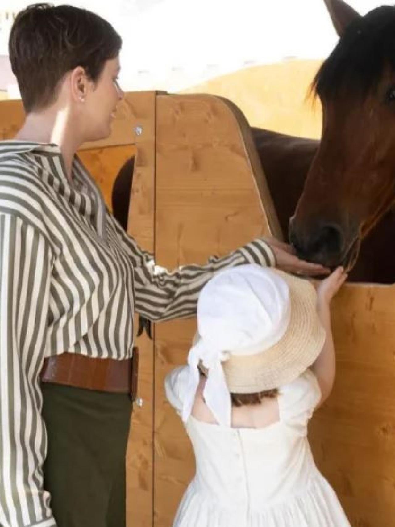 Gabriella acariciando un caballo junto a su madre, Charlène.