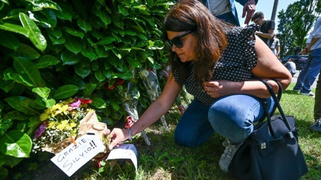 Una mujer colocando flores a las puertas de la mansión de Berlusconi.