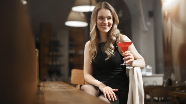 Una mujer en la barra de un bar toma un cóctel.