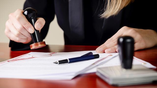 Primer plano de las manos de un notario que está sellando un documento.