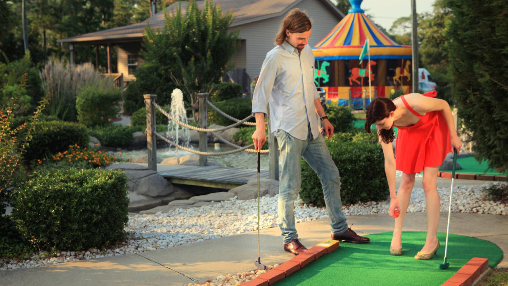 Una pareja jugando al minigolf.