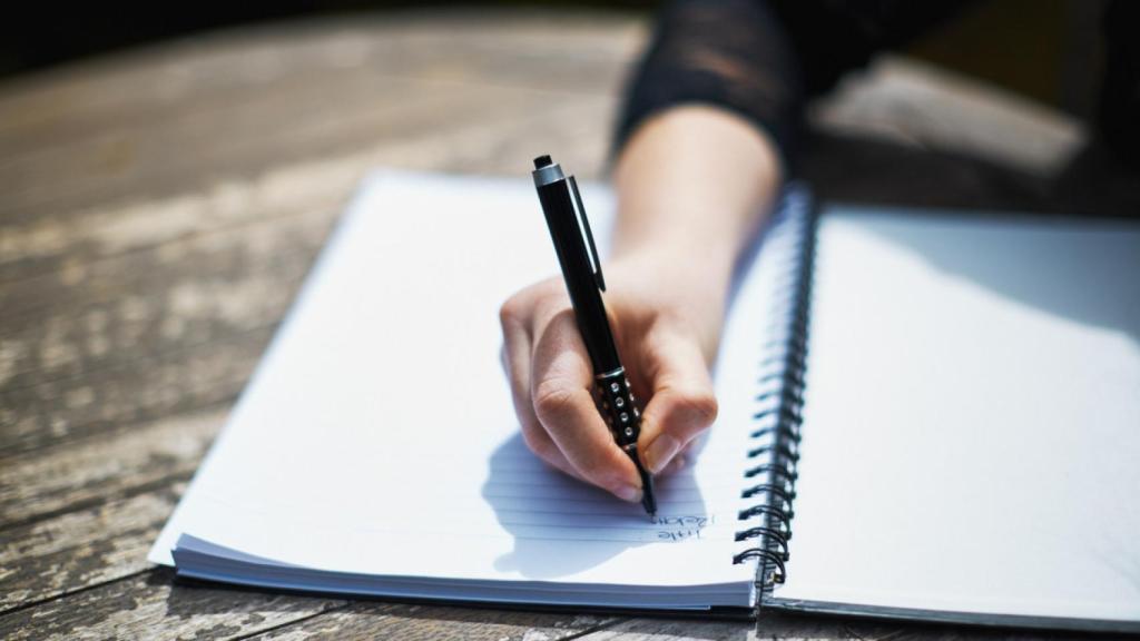Imagen de archivo de una mujer escribiendo en un cuaderno.