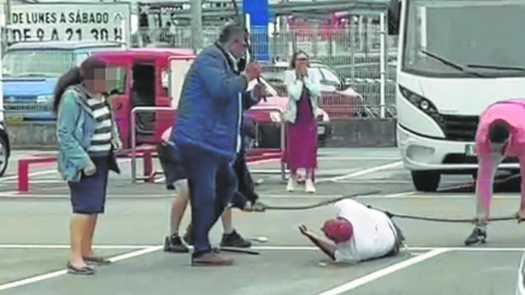 El  vigilante, en el suelo, mientras es agredido con barras de hierro por tres hombres.