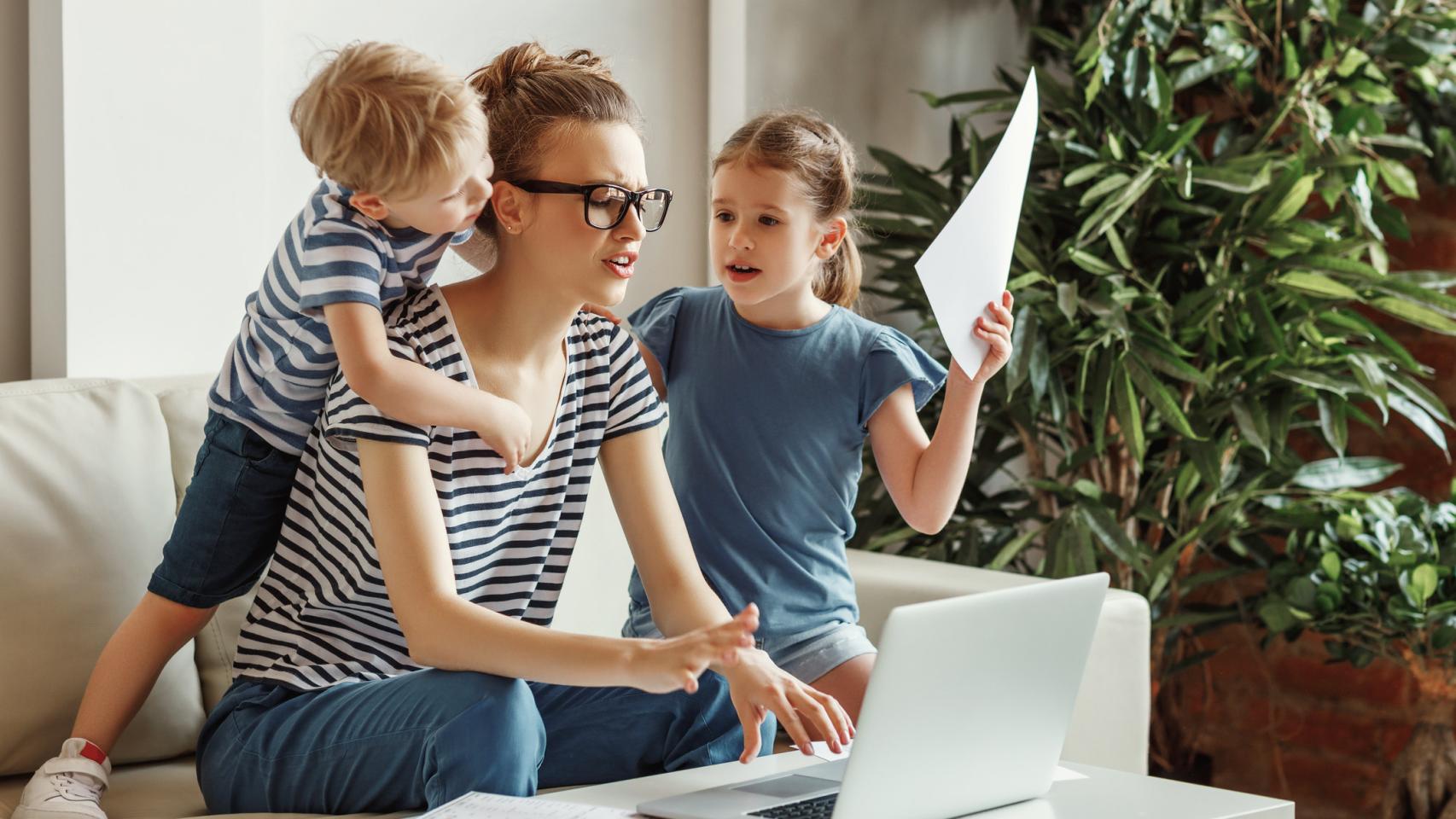 Imagen de archivo de una mujer intentando trabajar con sus hijos en casa.