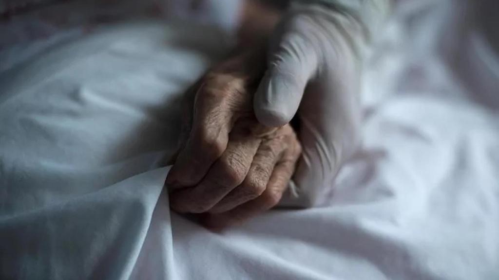 Una sanitaria coge la mano de una persona mayor, en imagen de archivo.
