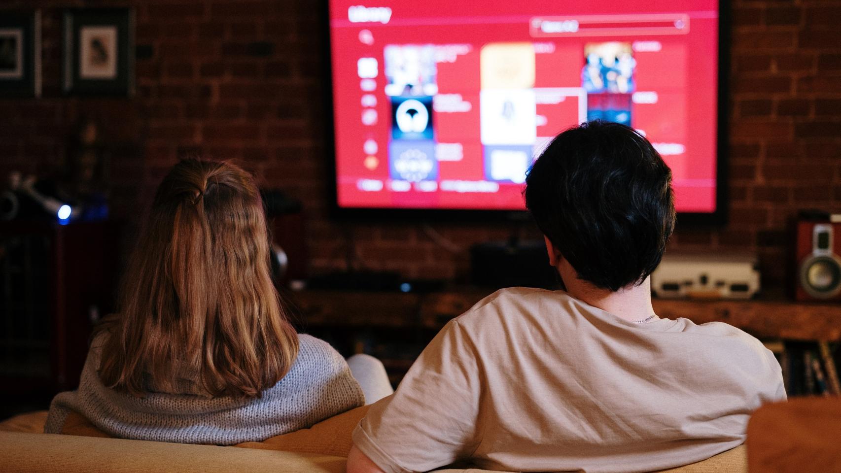 Una pareja viendo la televisión en su domicilio.