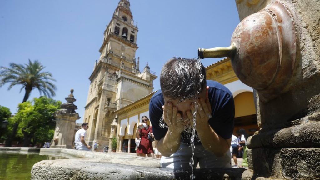 Un turista se refresca en una de las fuentes del patio de los naranjos de la Mezquita de Córdoba.