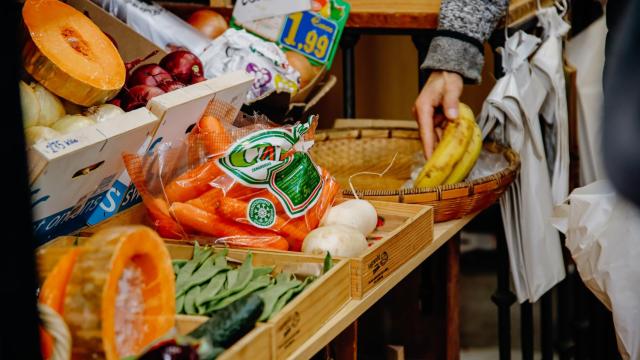 Una persona cogiendo plátanos en una frutería de Madrid.