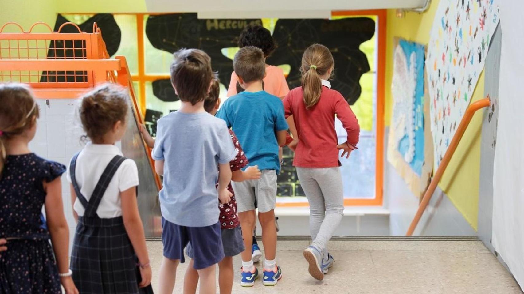 Varios niños bajan las escaleras de un colegio.