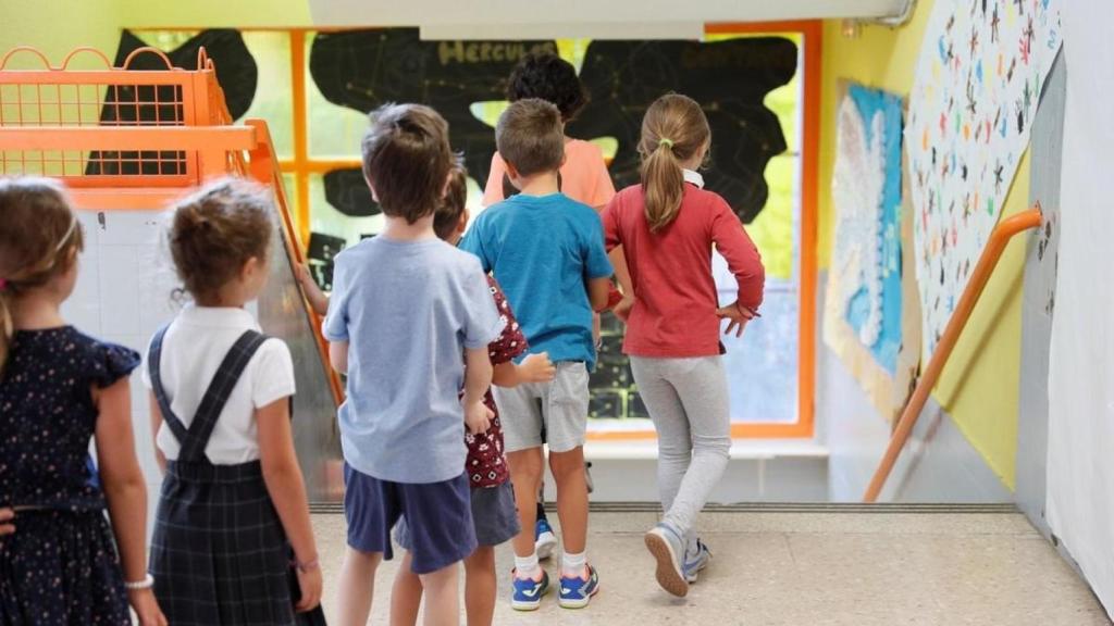 Varios niños bajan las escaleras de un colegio español.