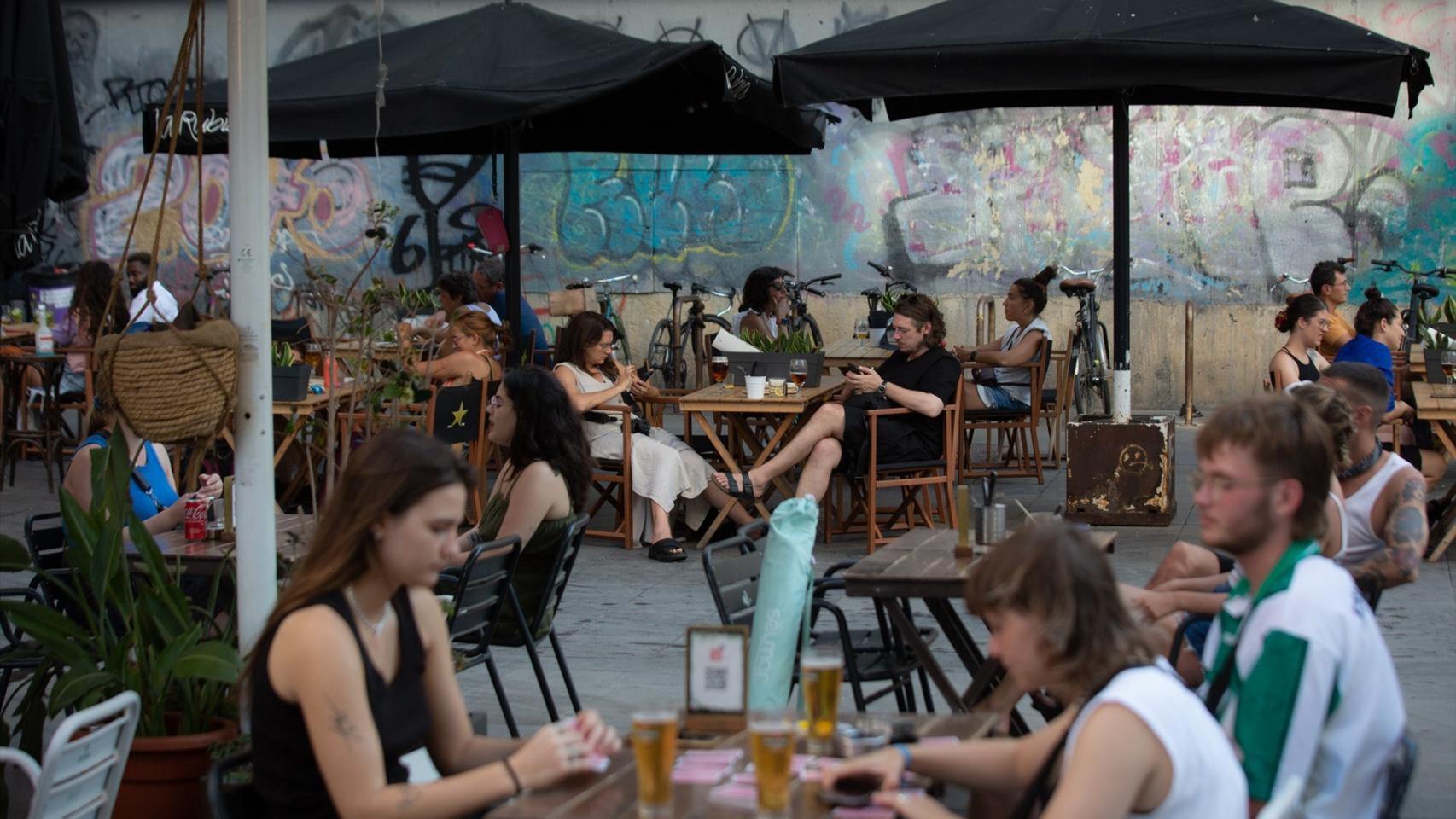 Varias personas sentadas en bares en la plaza dels Àngels del Raval, en Barcelona.