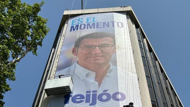 Dos operarios terminan de desplegar la lona con el lema del PP en la sede de la calle Génova.