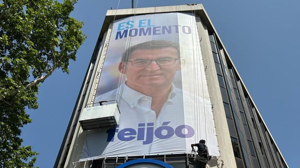 Dos operarios terminan de desplegar la lona con el lema del PP en la sede de la calle Génova.
