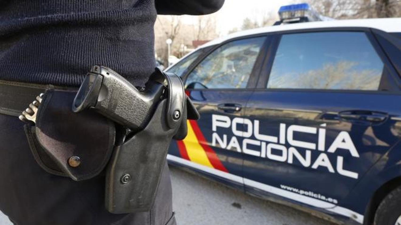 Agente de la Policía Nacional junto a un coche oficial