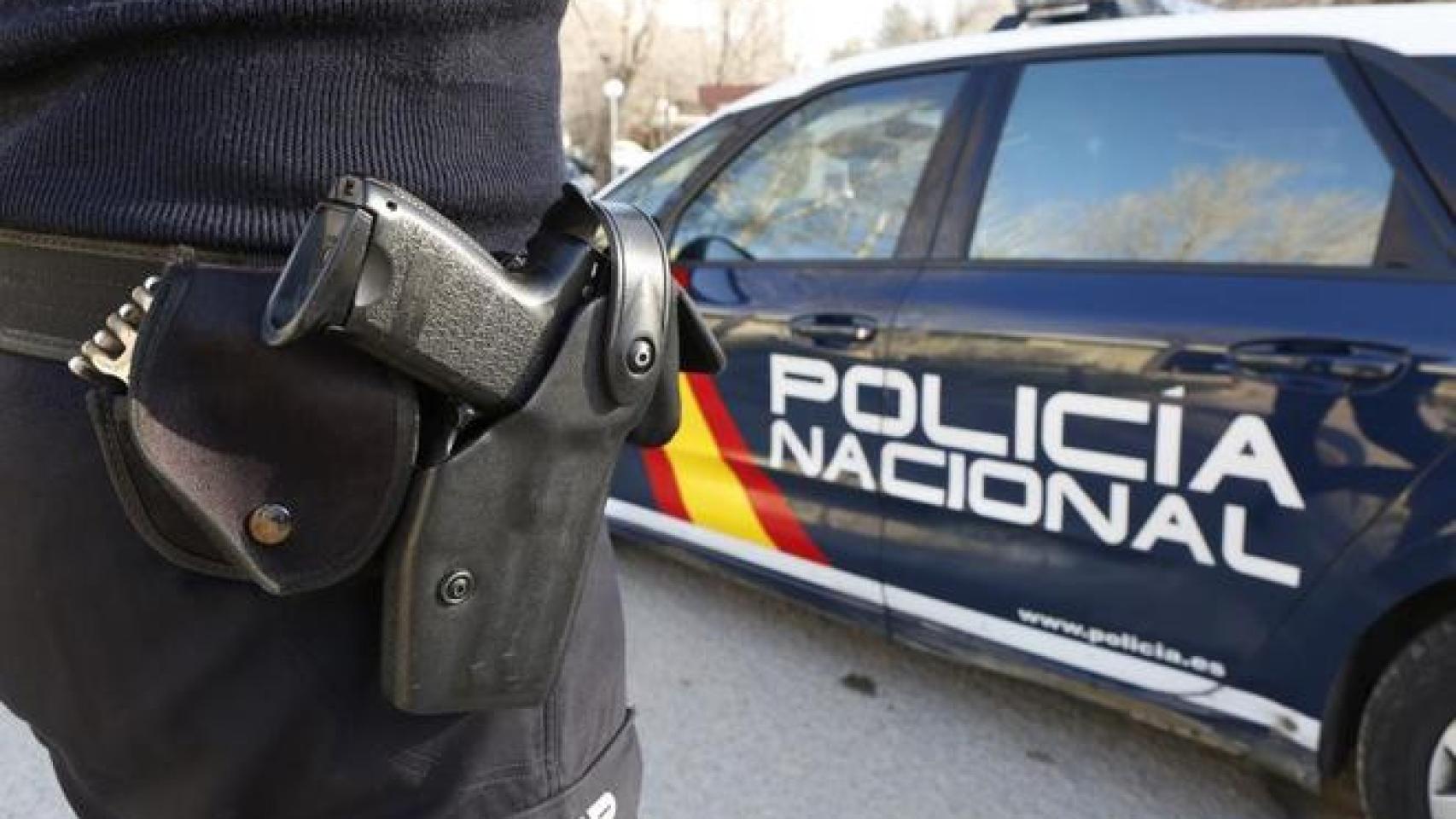 Agente de la Policía Nacional junto a un coche oficial