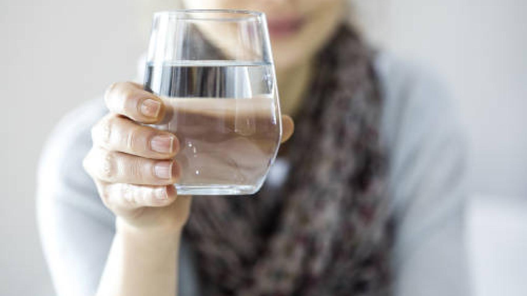 Una joven sostiene un vaso de agua.