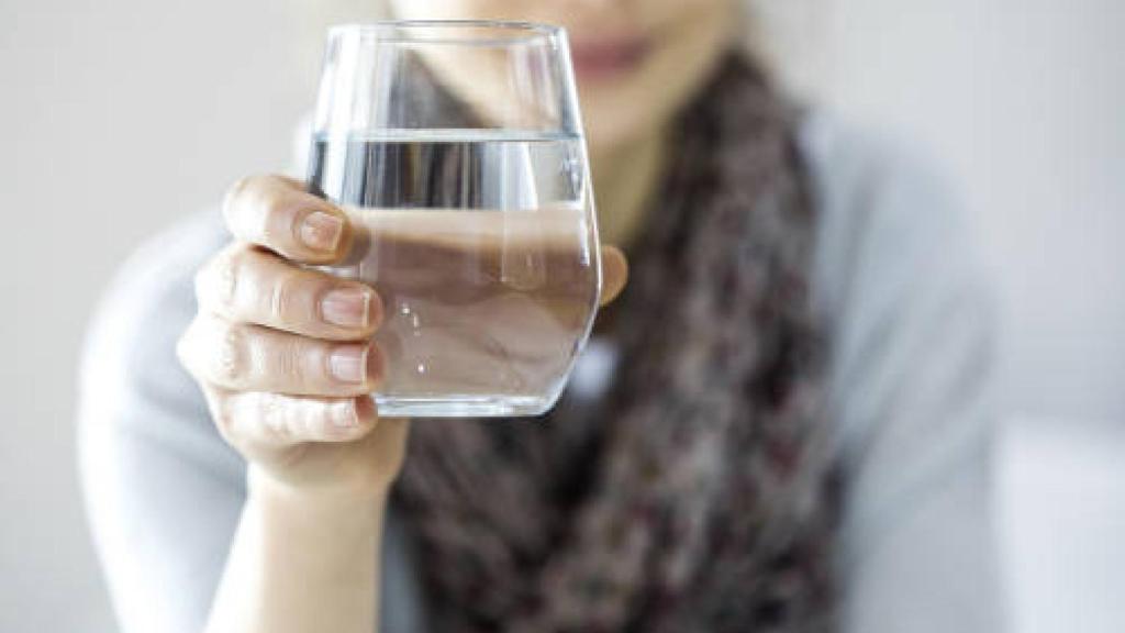 Una joven sostiene un vaso de agua.