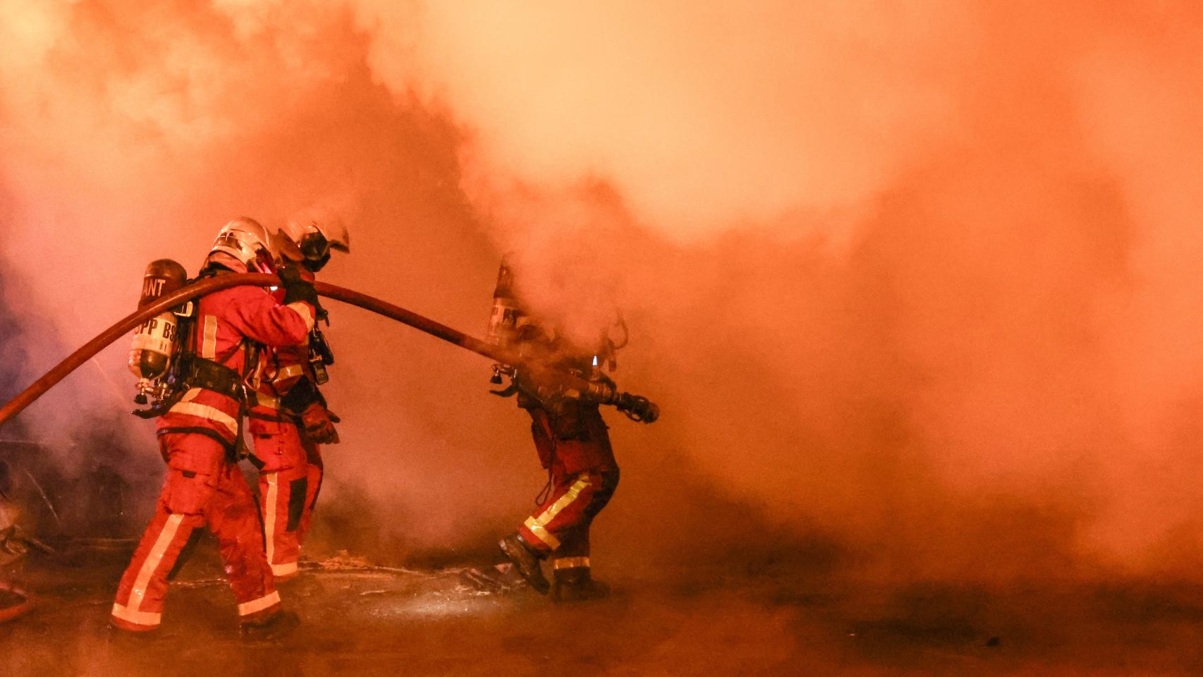Bomberos franceses apagan un autobús en llamas.