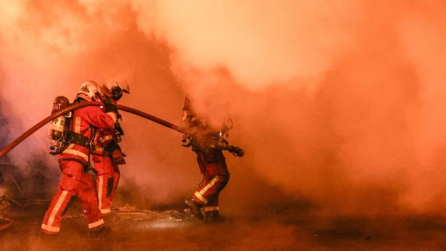 Bomberos franceses apagan un autobús en llamas.