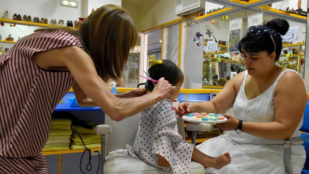 Tita le corta el pelo a la pequeña Celia, con su mamá María al lado