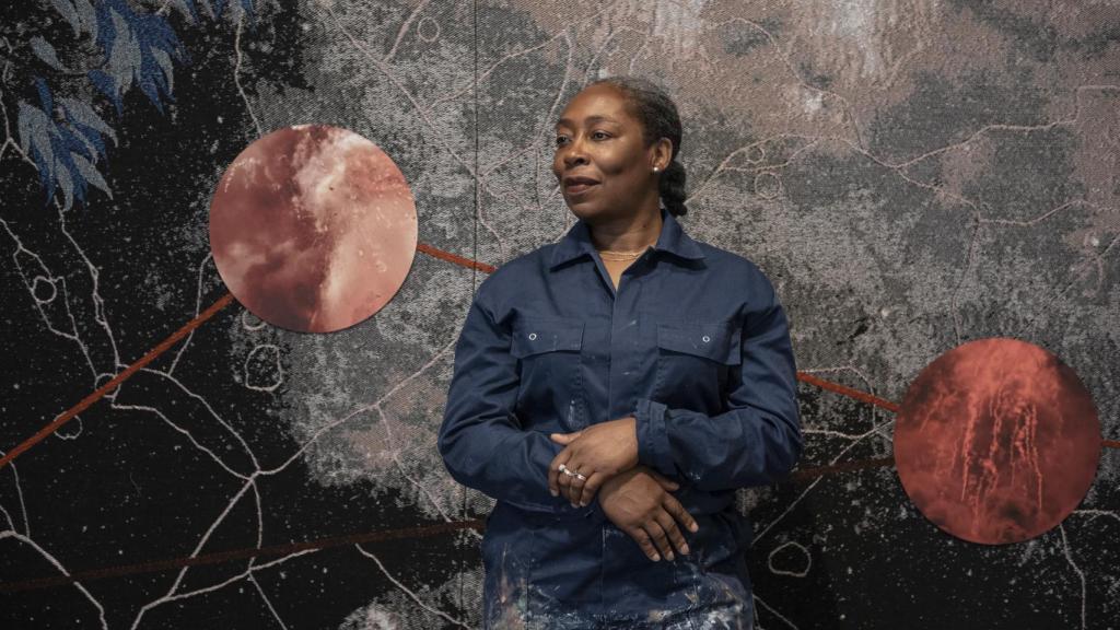Otobong Nkanga junto a su tapiz 'Double Plot' (2018), durante el montaje de la exposición. Foto:  Ariadna García / IVAM
