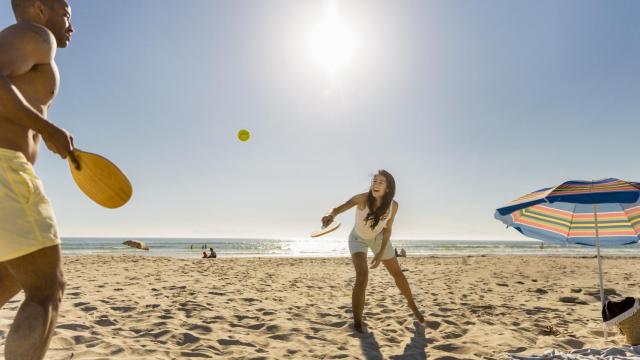 Dos chicos juegan en la playa con dos palas.