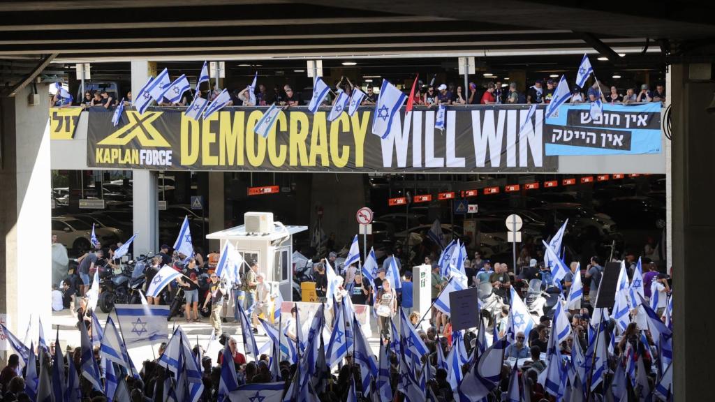 Manifestantes ondean banderas y pancartas en el aeropuerto Ben-Gurión de Tel Aviv, este martes.