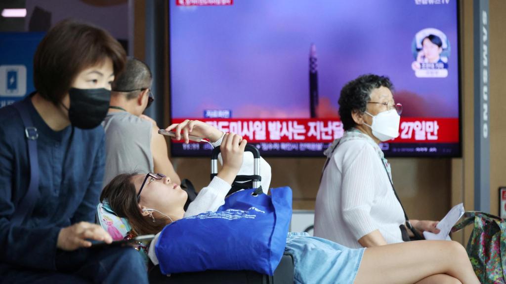 Los pasajeros esperan su tren frente a un televisor que transmite un informe de noticias sobre Corea del Norte disparando un misil balístico frente a su costa este, en una estación de tren en Seúl, Corea del Sur.