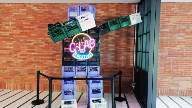 Figura hecha con cajas de plástico y luces de neón en la entrada de C-Lab.