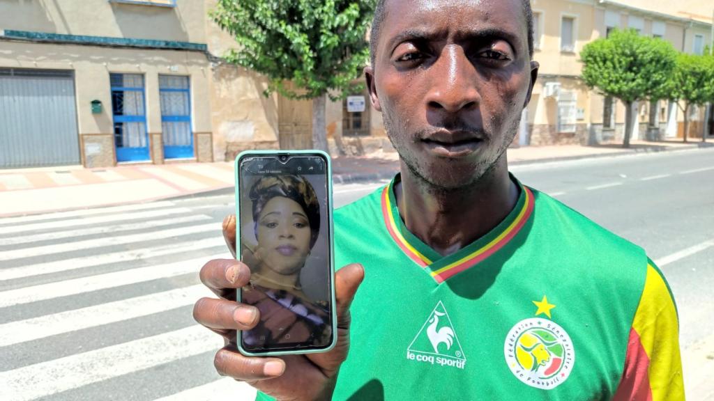 Khadj Sy, este lunes, mostrando una foto de su esposa, Astou, junto al paso de peatones donde fue atropellada.
