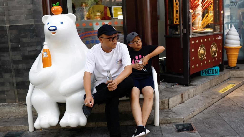 Dos personas descansan fuera de una tienda en medio de la alerta naranja por ola de calor, en Beijing , China, 5 de julio de 2023.