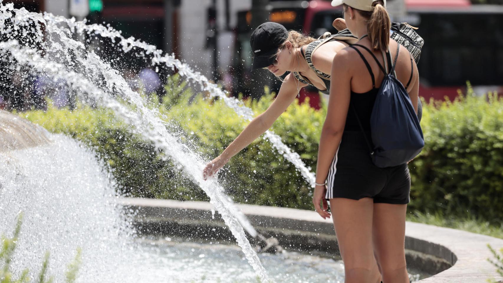 Varias personas refrescándose en una fuente en plena ola de calor, esta semana.