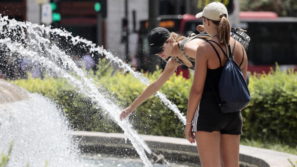 Varias personas refrescándose en una fuente en plena ola de calor, esta semana.