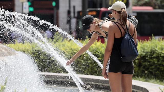 Varias personas refrescándose en una fuente en plena ola de calor, esta semana.