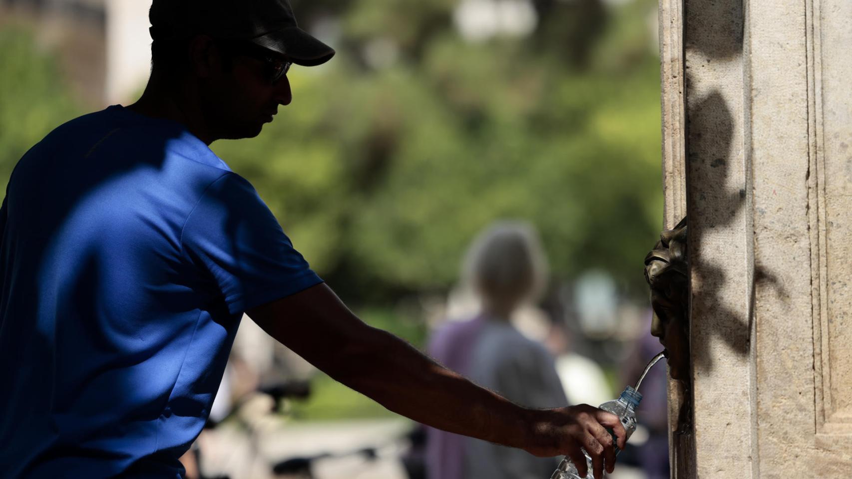 Un hombre rellena una botella de agua en una fuente pública en plena ola de calor.