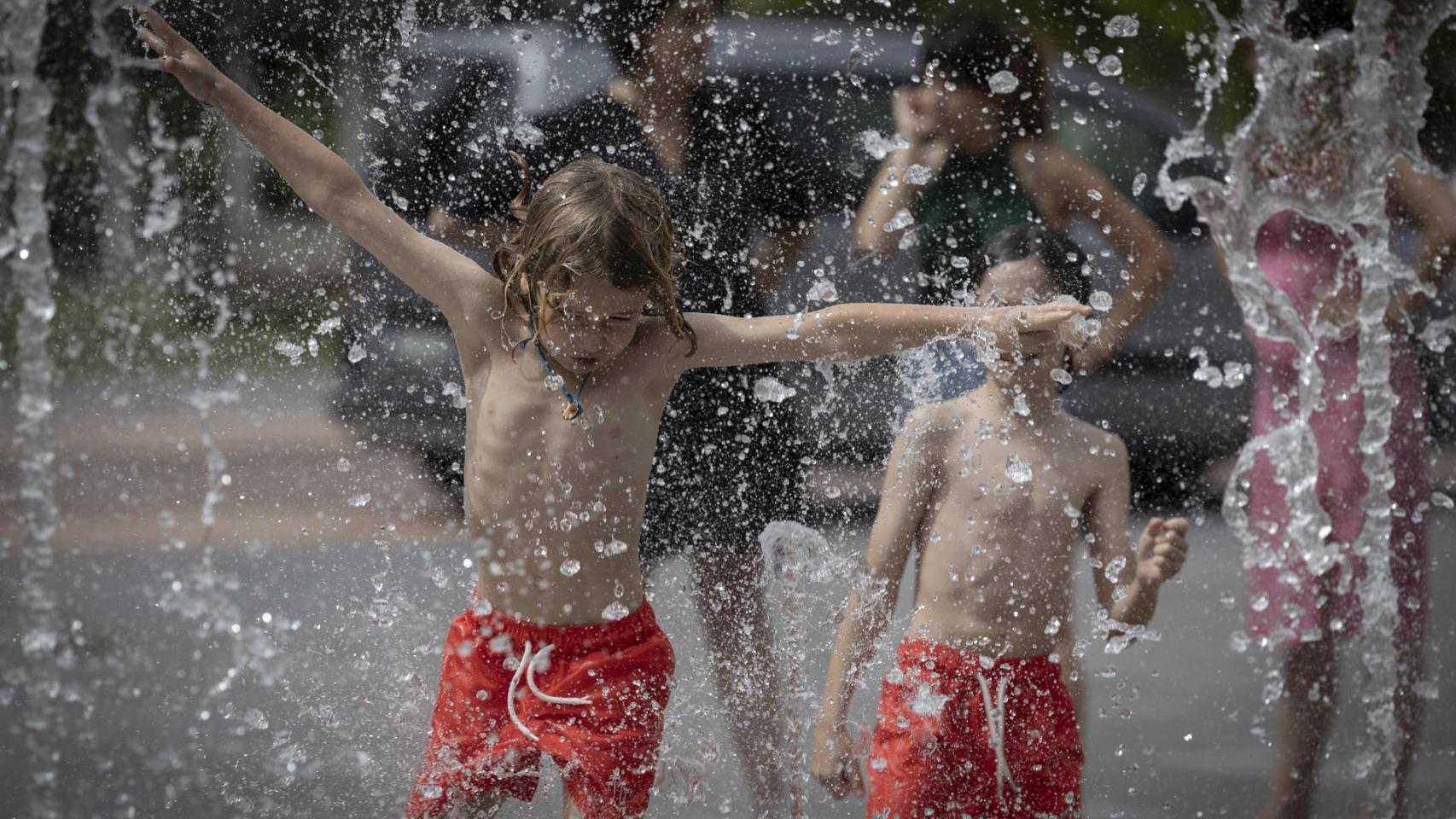 Dos niños bañándose en una fuente.