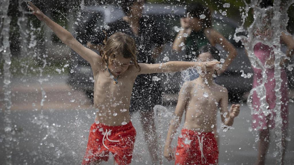 Dos niños bañándose en una fuente.