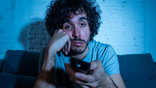 Imagen de archivo de un hombre aburrido viendo la televisión.